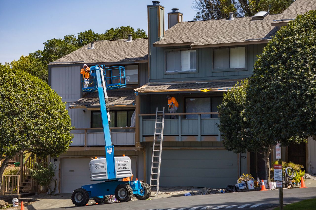 Mastering the First Impression: Your intriguing post title goes here House being renovated with workers on a hydraulic lift in an urban area.